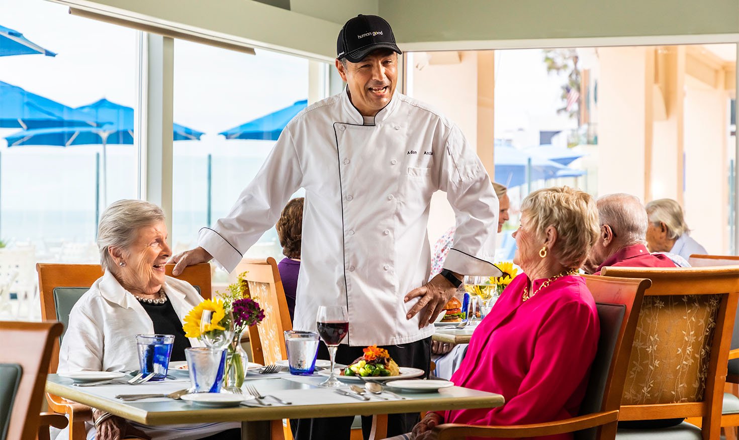 Chef chatting with two senior women while they are dining in the White Sands dining venue