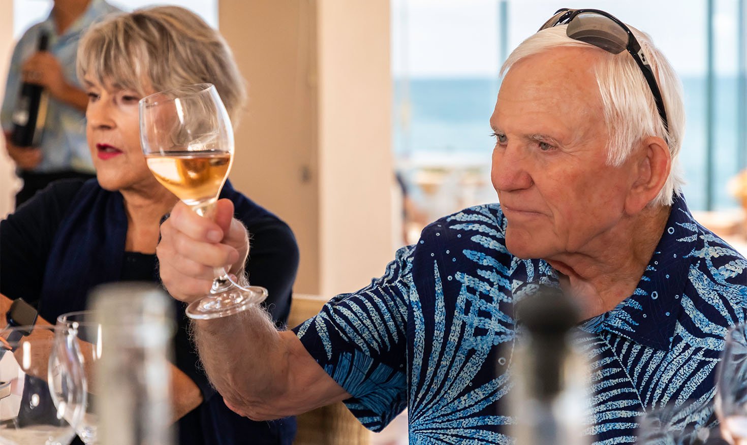 Senior man inspecting a glass of white wine at a wine tasting event