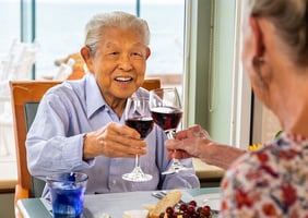 Seniors toasting with glasses of red wine at lunch