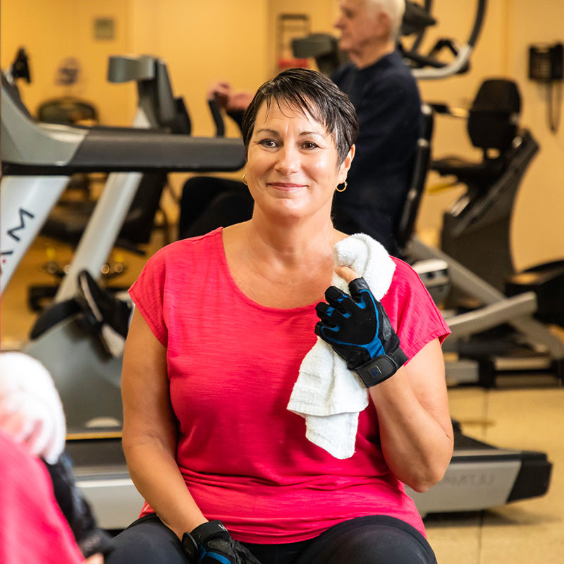 Woman holding a towel sitting in the White Sands fitness center