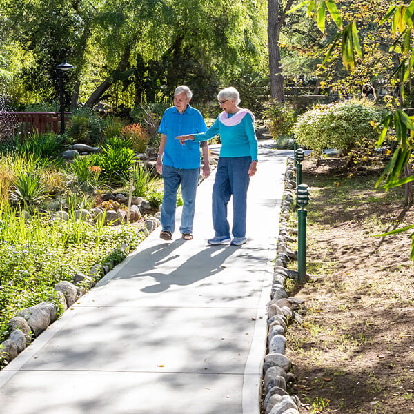 Senior couple walking on a paved path through the landscaped grounds of Westminster Gardens