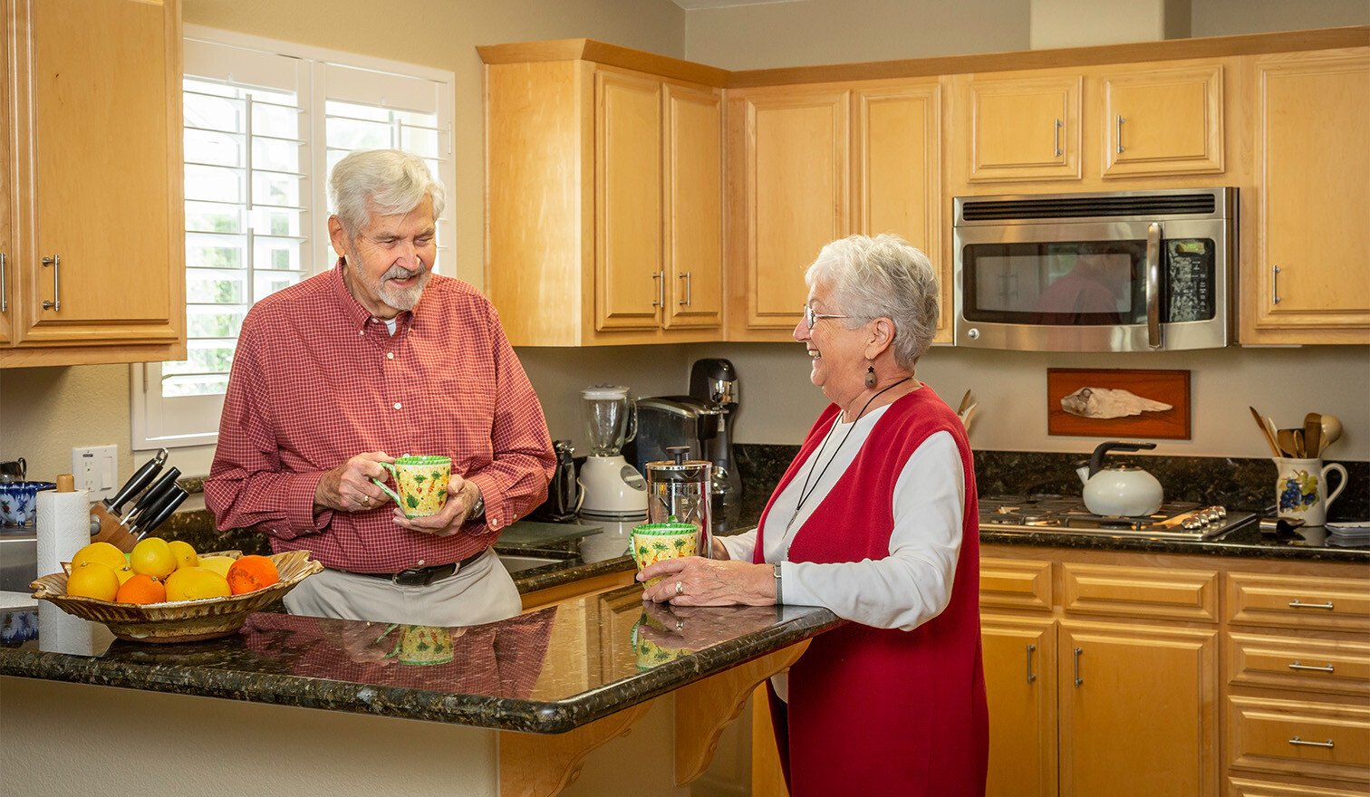 Senior couple holding mugs in the kitchen of their Westminster Gardens home