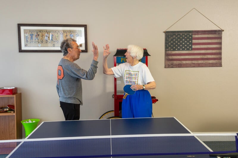 Senior man and woman high-five near table tennis table