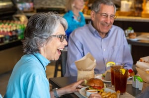 Senior woman laughing while eating lunch with a senior man