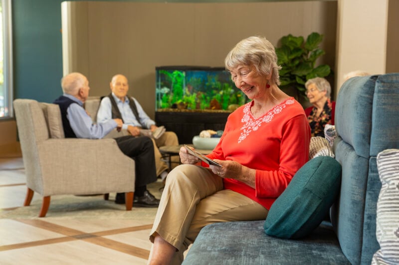 Seniors sitting in a common area with a fish tank at Piedmont Gardens