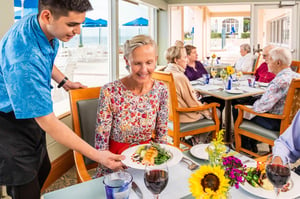 Senior woman being served a meal at the White Sands dining room