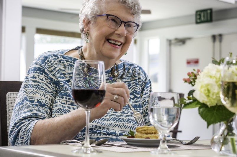 Senior woman eating in the dining room at Redwood Terrace