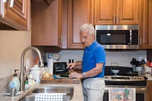 Senior man chopping vegetables in the kitchen of his home at Redwood Terrace