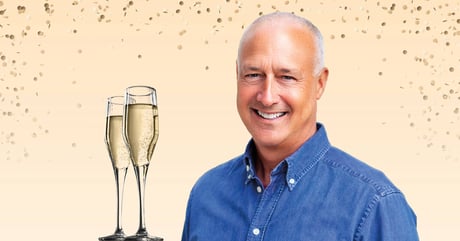 CEO John Cochrane smiling with confetti and champagne glasses on a light beige background.