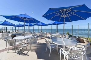 Oceanfront patio tables with chairs and umbrellas