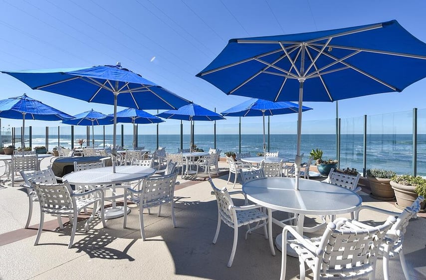 Oceanfront patio tables with chairs and umbrellas