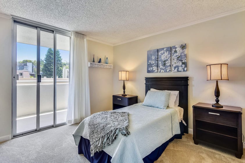 Bedroom in an apartment at Piedmont Gardens with a sliding glass door that leads to a balcony