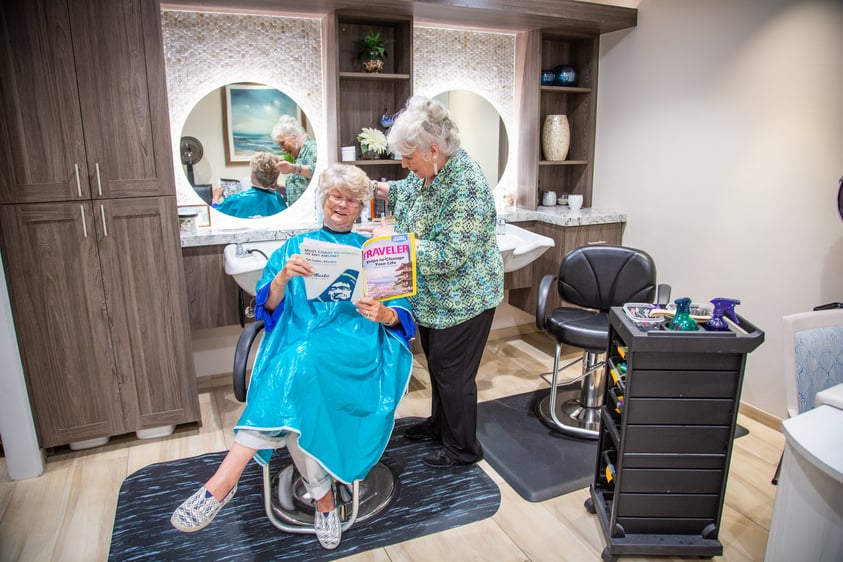 Senior woman reading a magazine in a salon chair in the White Sands beauty salon