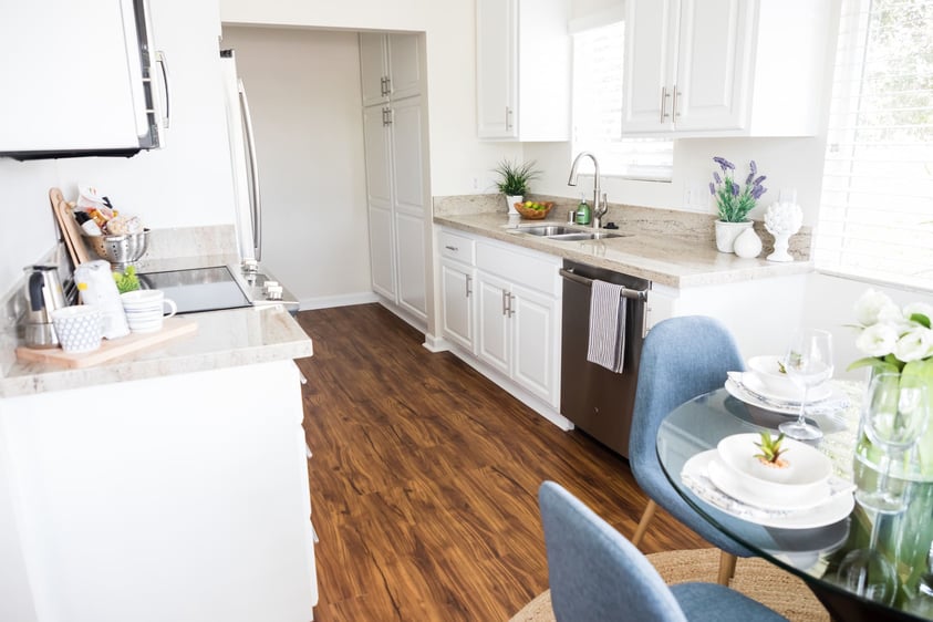 Galley kitchen with white cabinets, granite countertops, and wood floors in a home at Redwood Terrace