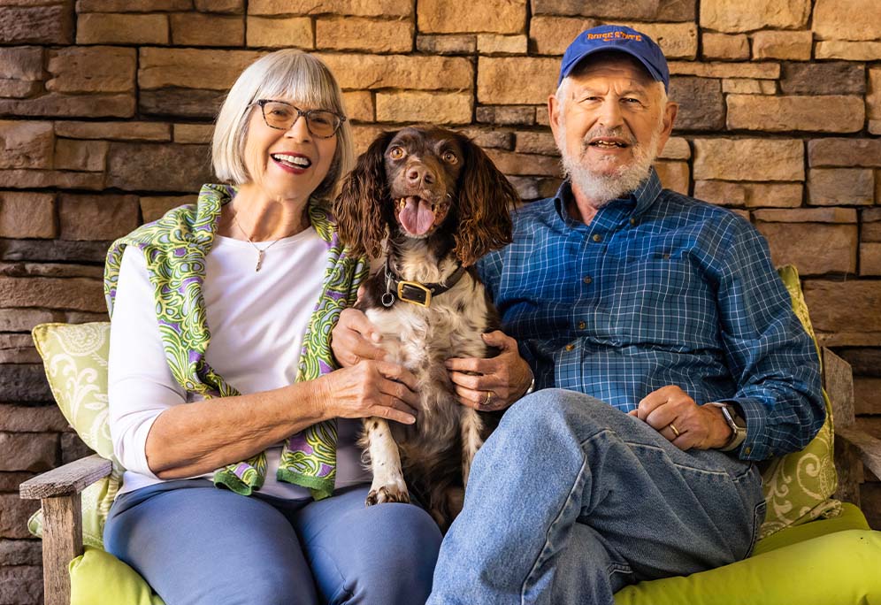 senior couple sitting on an outdoor bench with their dog