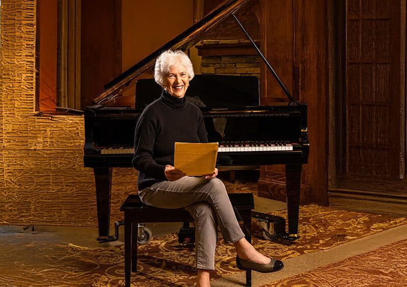 Senior woman holding sheet music and sitting on a piano bench