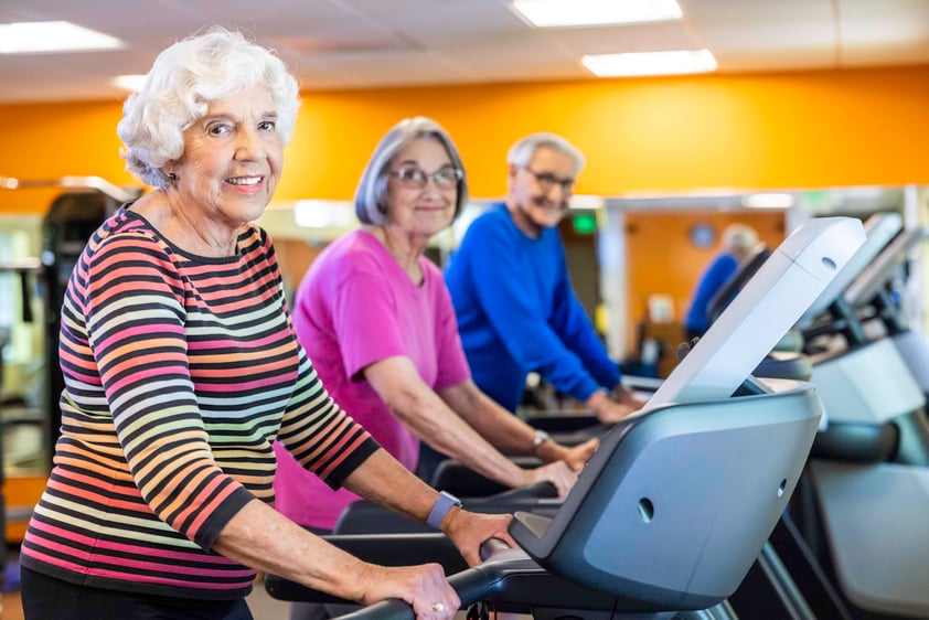 Seniors walking on treadmills in the fitness center at The Terraces of Los Gatos