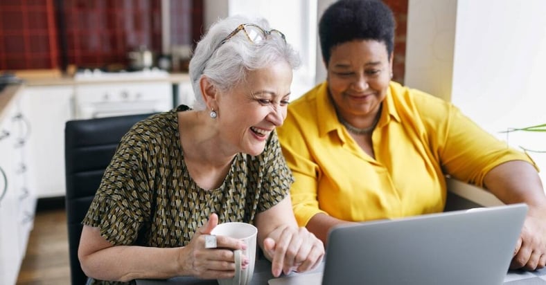 two women smiling and looking at laptop