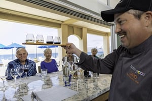 Bartender holding a flight of wine glasses to a group of seniors during a wine tasting