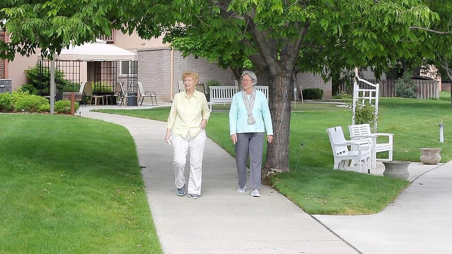 Two senior women walking on the sidewalk through The Terraces at Summitview