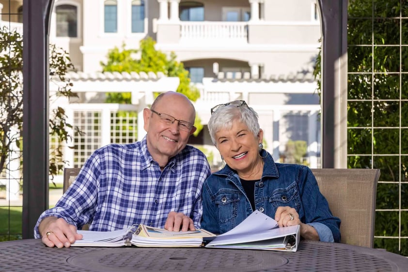 Senior couple smiling for a photo with binders on the table