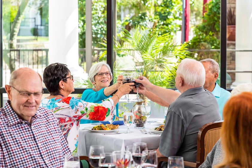 Two senior couples toasting their wine glasses at dinner table