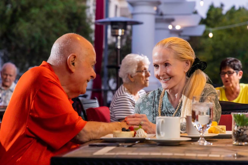 Elderly couple holding hands at dining table
