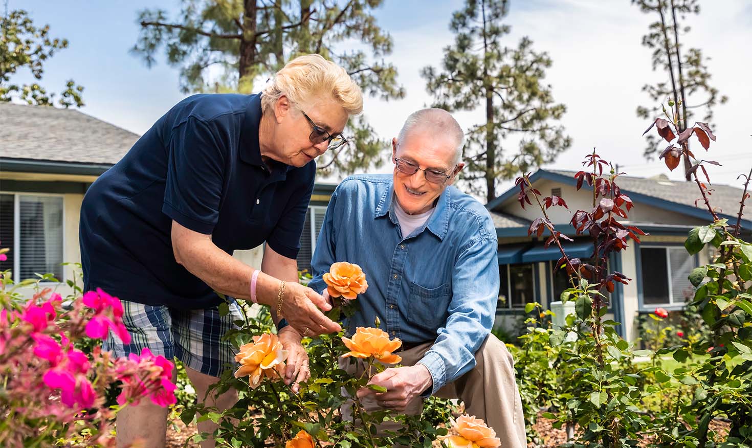 Senior couple looking at orange roses in the garden at Redwood Terrace