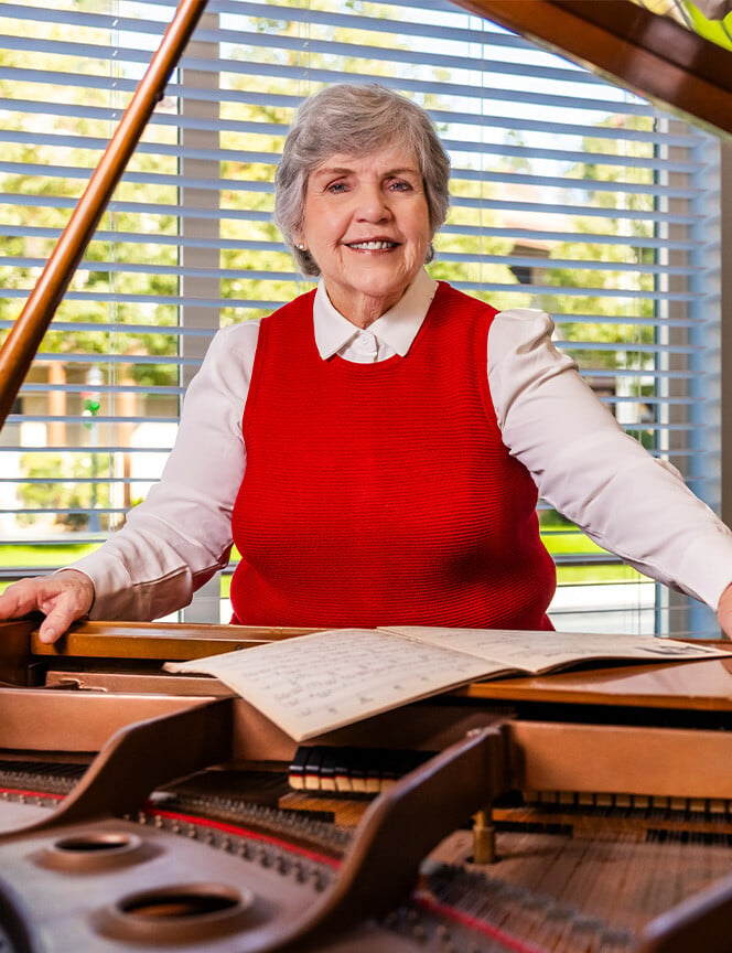 Senior woman standing at grand piano
