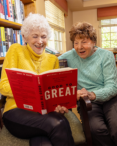 senior friends reading a book inside library