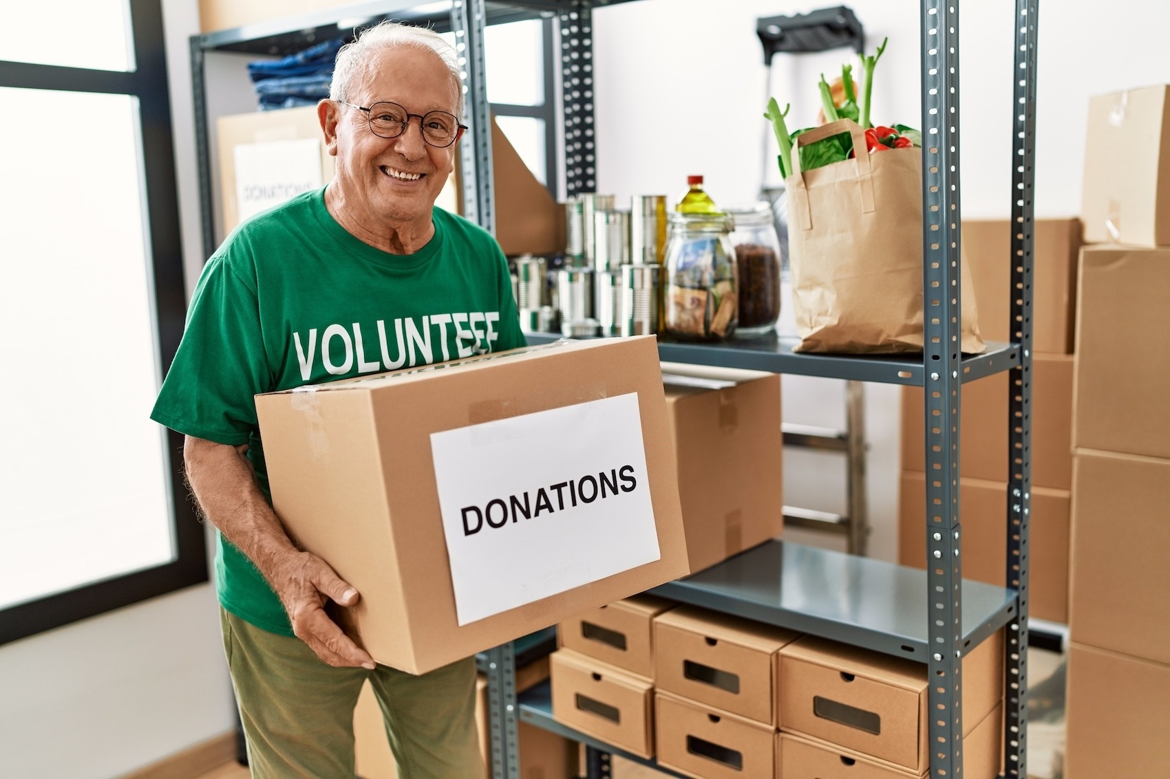 older man holding a box of donations as a volunteer