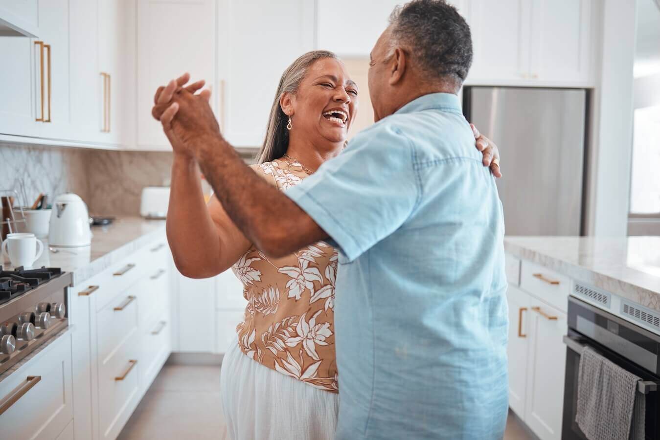 older man and woman dancing and smiling in their kitchen