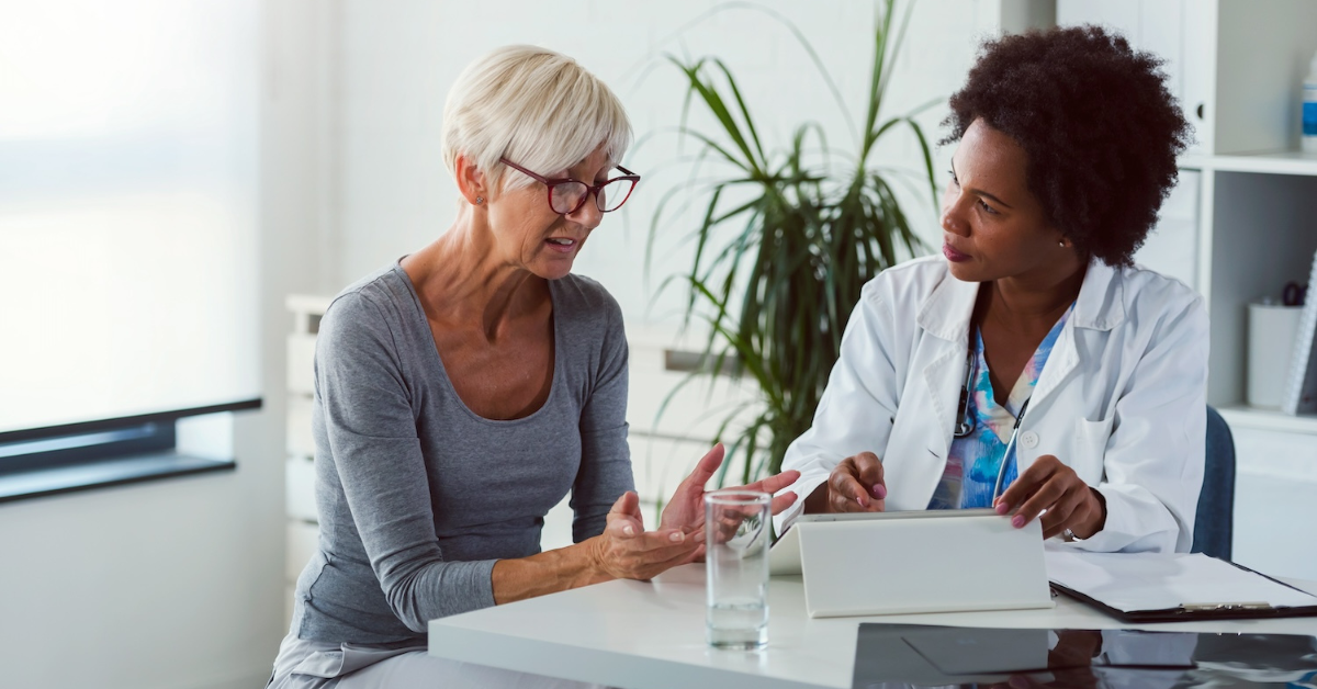 woman sitting at a desk talking to her doctor about potential dementia misdiagnosis