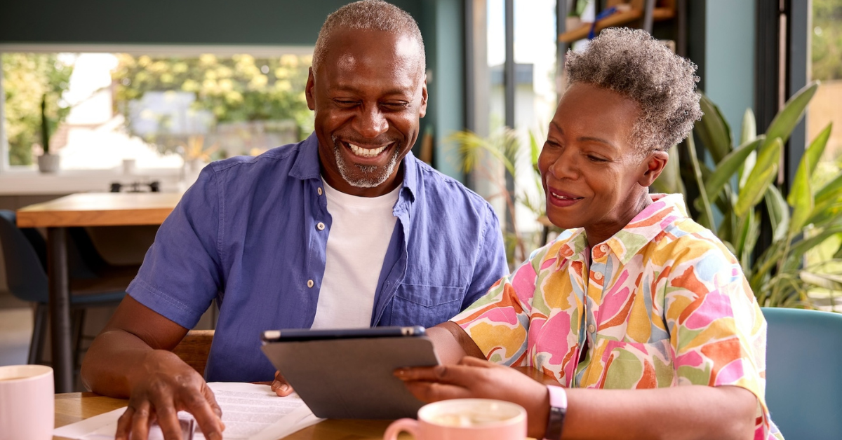 man and woman sitting at table on tablet going through finances