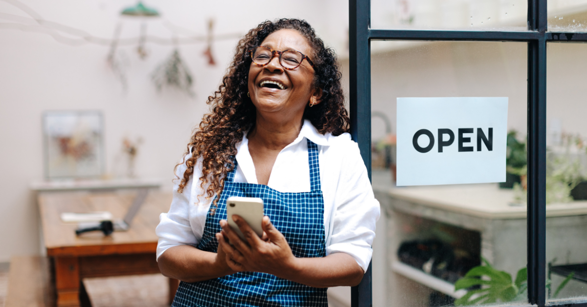 woman smiling outside storefront with open sign