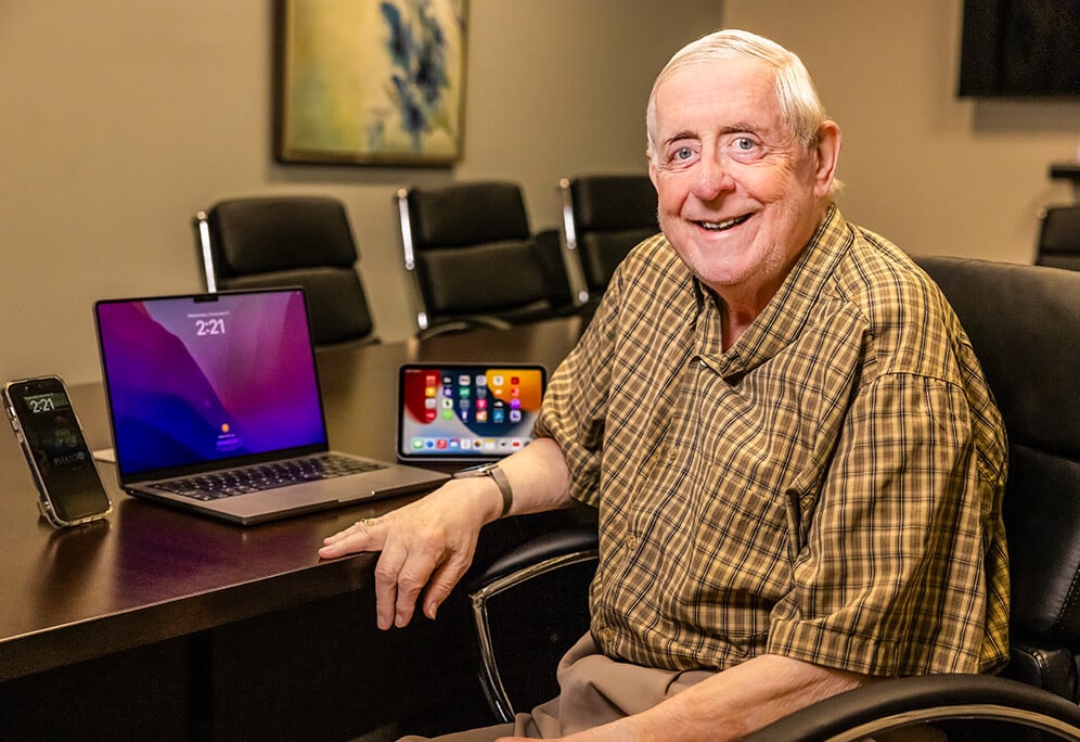 Ron sitting in conference room with multiple electronic devices